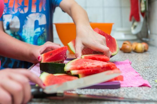Süße Erfrischung: zwei Bewohner des Jugendhilfezentrums schneiden in der Gemeinschaftsküche Melonen in saftige Stücke.