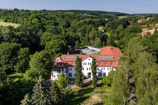 Luftaufnahme: Blick auf die Gebäude der Förderschule und des Jugendhilfezentrum, die von idyllischem Wald umgeben sind.