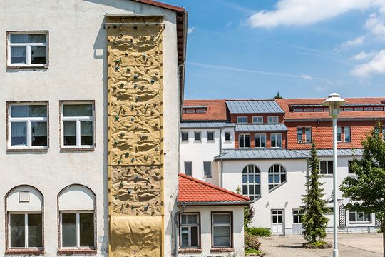 Das modern restaurierte Schulgebäude der Förderstufe, die sich dem Jugendhilfezentrum in Bad Köstritz direkt anschließt. An der Fassade ist eine Outdoor Kletterwand angebracht, die über 3 Etagen bis zum Dach reicht.